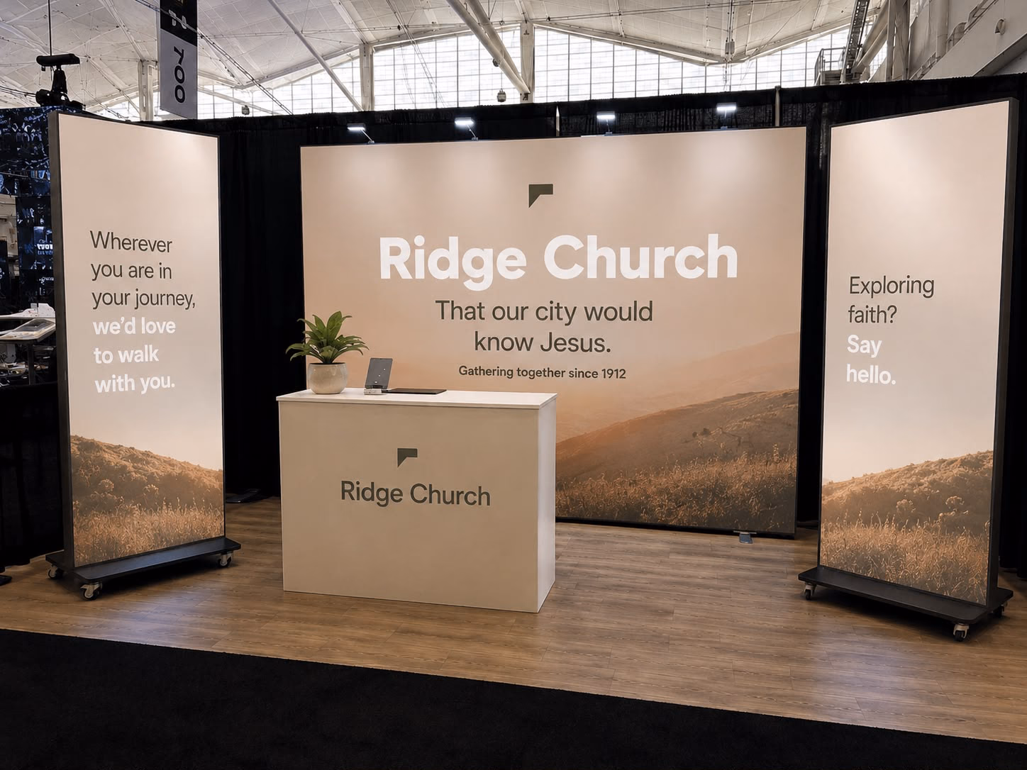 A conference booth for Ridge Church: a wide LED wall between two LED totems, with a white counter in front.