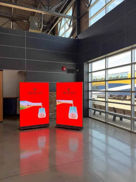 Two LED totems showing a Mionetto prosecco ad in a train station hall